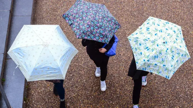 Three people walking holding umbrellas