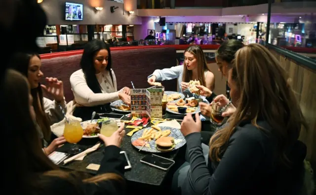 Six woman eat together in a pub in London