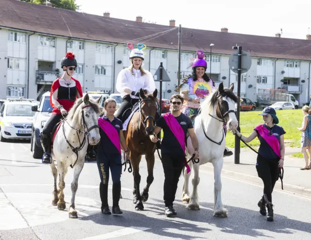 Modern day Godivas selected by public nomination ride on horseback from various wards of the city accompanied by women bearing banners and flags representing their manifesto for the city