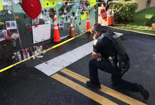 A Miami policeman prays at a memorial to the victims