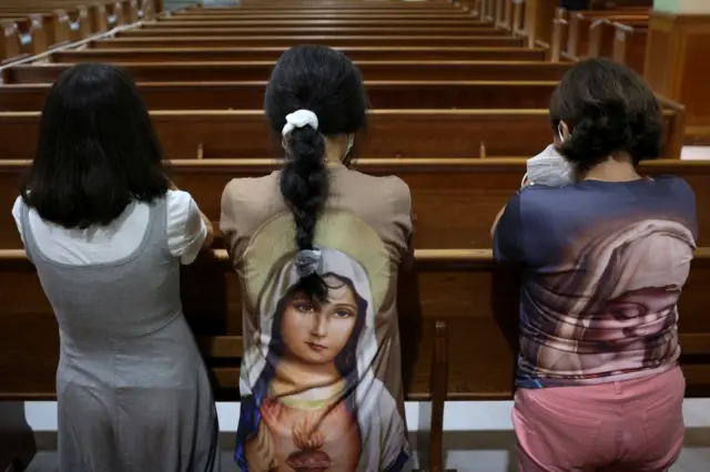 People pray during a mass at the Saint Joseph Catholic Church near the site of a partially collapsed residential building