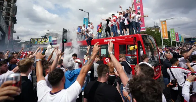 Fans climb on top of a bus