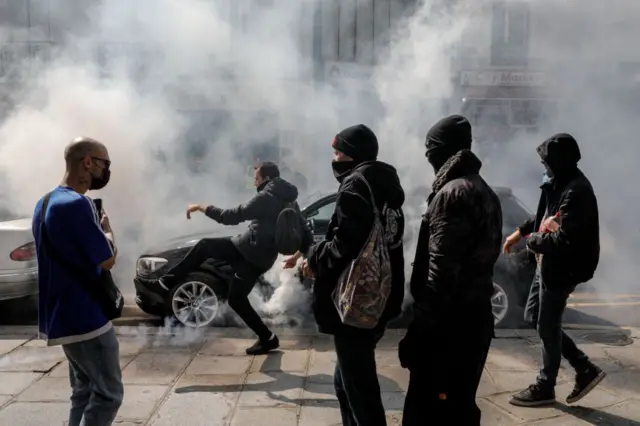 A demonstrator kicks back a gas canister to Police on the sidelines of a protest in central Paris on July 14, 2021