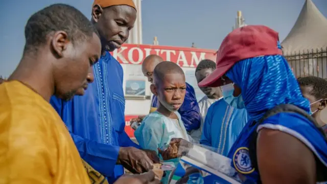 People buy covid-19 protection masks before entering into the Massalikul Jinaan Mosquee during the celebrations of Aid al-Fitr, also known as Korite in Western Africa, in Colobane, Dakar, Senegal,