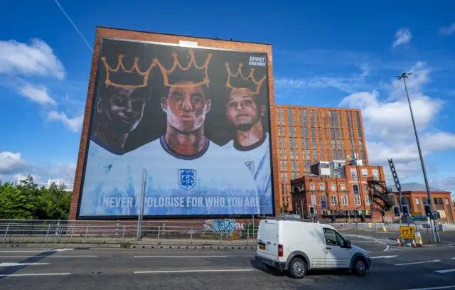 A digital mural of England players Marcus Rashford, Jadon Sancho and Bukayo Saka in Manchester