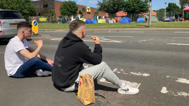 Two men outside the factory