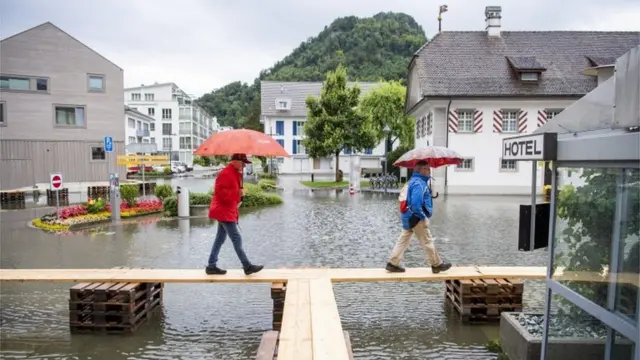 People walk over planks amid flooding in Switzerland