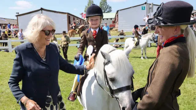 Camilla strokes a horse