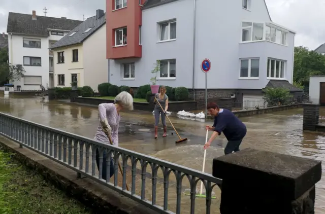 Women try to clear a street from the floods in Mayen