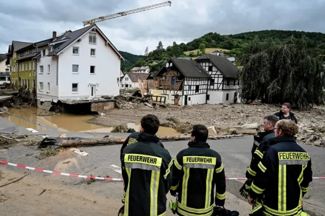 Firefighters stand at a damaged area of the village of Schuldt, Germany. Photo: 15 July 2021