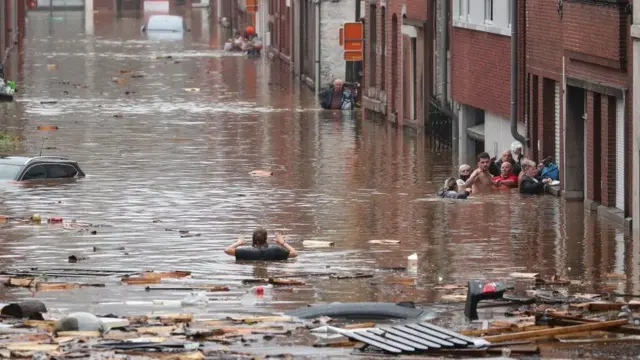 People wade through flood water in the Belgian city of Liège