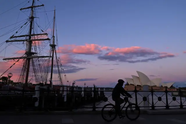 A person rides a bicycle past the Sydney Opera House in Sydney on July 17, 2021