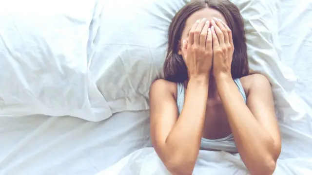 Woman with hands on face in bed