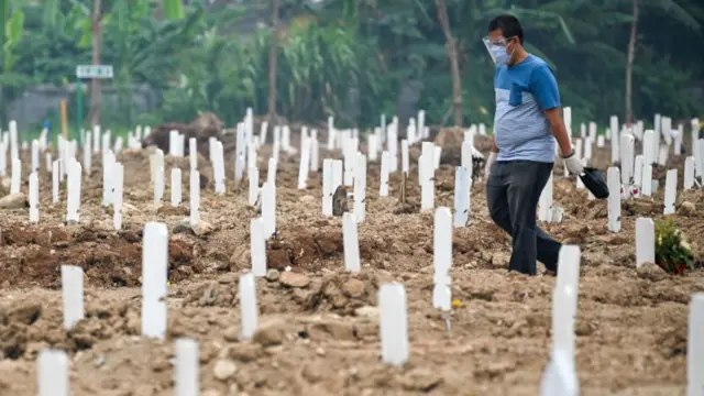 A family member visits his relative's grave at a cemetery for Covid victims in Jakarta