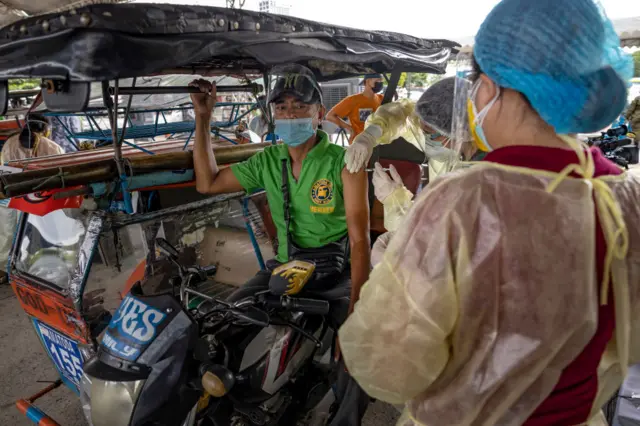 A public transportation worker is inoculated with Sinovac Biotech's CoronaVac COVID-19 vaccine during a mass vaccination for public transportation workers on July 20, 2021 in Manila, Philippines