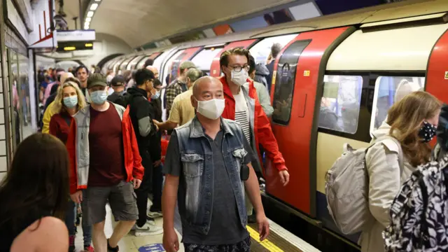 People wearing protective face masks walk along a platform on the London Underground, amid the coronavirus disease (COVID-19) outbreak, in London, Britain