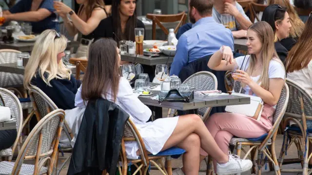 A group of people sitting at a bar table outside