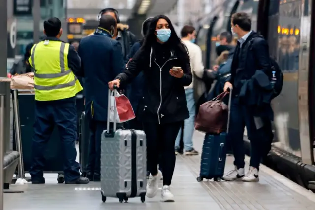 A woman wearing a mask as she walks in a train station