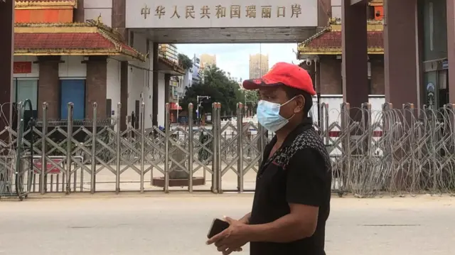 A man walks past the China-Myanmar border gate in Muse in Shan state on July 5, 2021, as the Chinese city of Ruili near the border with Myanmar imposed a lockdown and started mass testing.