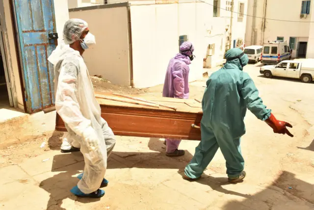 Tunisian municipality employees seen carrying a casket of a COVID-19 victim at the regional hospital