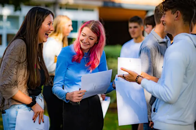 A group of friends chat and laugh as they share their results with each other at Taunton School in Somerset