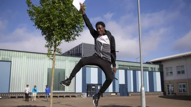 Student holding his results jumps in the air