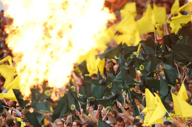 Flames as Norwich fans welcome the players on to the pitch for their home game with Liverpool