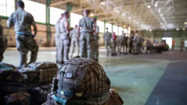 Armed forces and equipment seen inside aircraft hanger type building