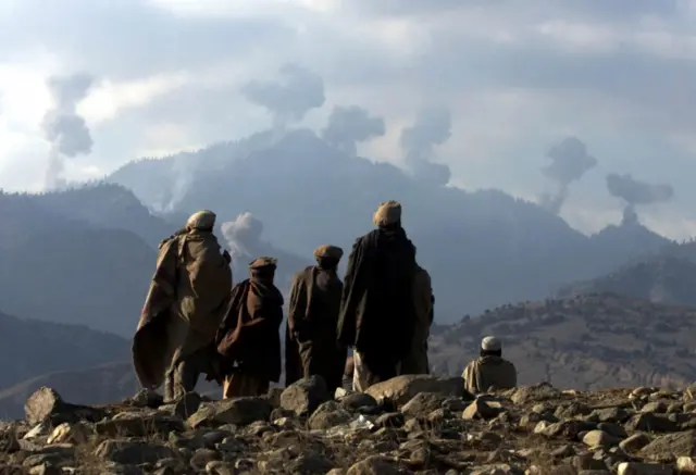 Anti-Taliban Afghan fighters watch several explosions from U.S. bombings in the Tora Bora mountains in 2001