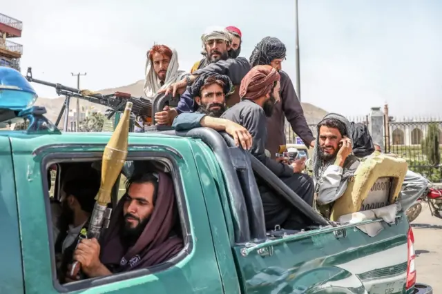 Taliban fighters are seen on the back of a vehicle in Kabul, Afghanistan