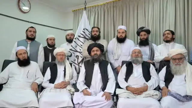 Mullah Baradar Akhund, a senior official of the Taliban, seated with a group of men, makes a video statement