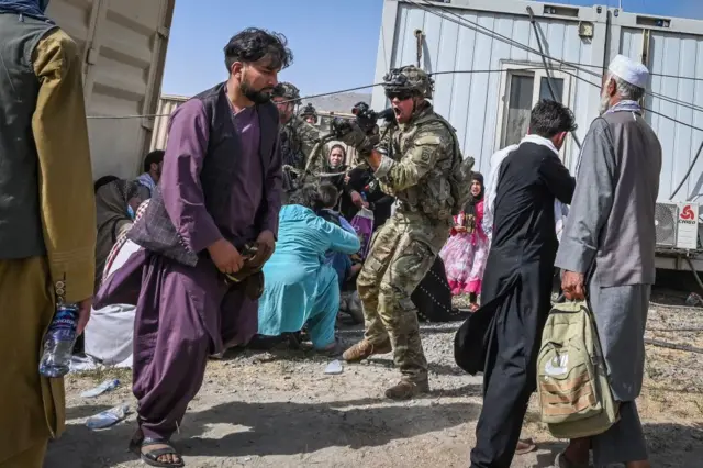 A US soldier points his gun towards an Afghan passenger at Kabul airport