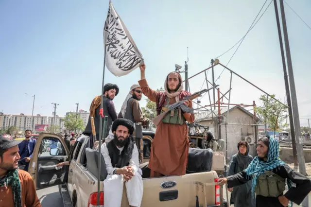 Taliban fighters are seen on the back of a vehicle in Kabul