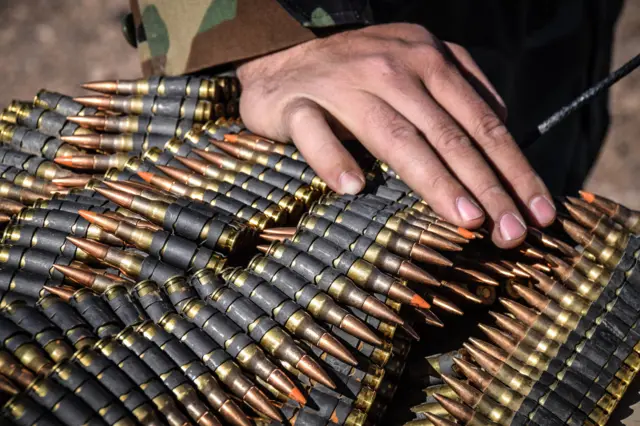 An Afghan Special Forces soldier resting his hand on M249 light machine gun bullets