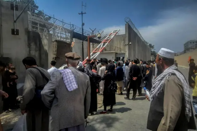 Afghan people gather outside the French embassy in Kabul