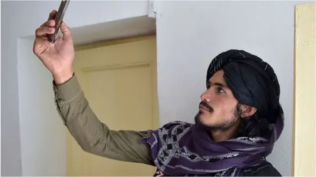 A Taliban fighter searches for a network signal for his mobile phone at a hospital