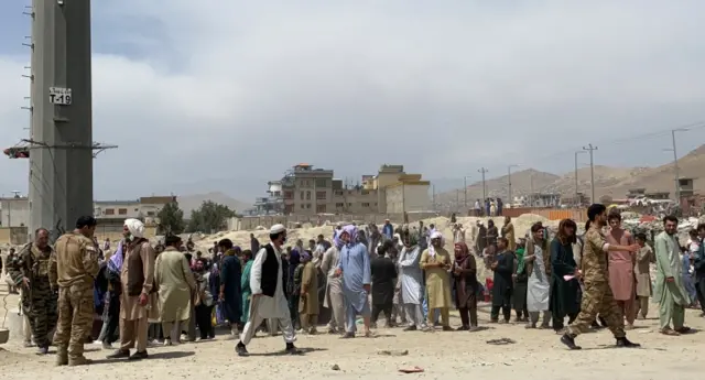 Afghans queue outside the Hamid Karzai International Airport to flee the country