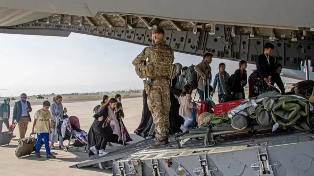 A handout picture provided by the British Ministry of Defence (MOD) shows British citizens and dual nationals residing boarding a military plane at the airport in Kabul, Afghanistan, 16 August 2021