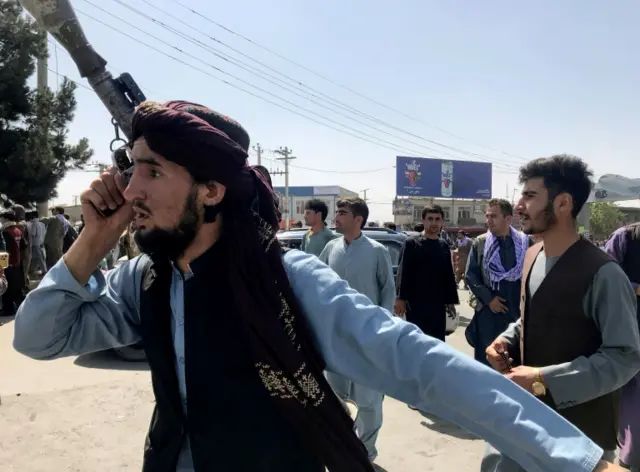 An Afghan fighter inspects the area at Kabul airport