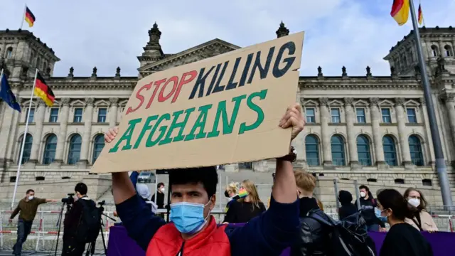 A man outside Reichstag building holds a 'Stop Killing Afghans' sign