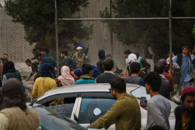 Taliban fighters use guns fire, whips, sticks and sharp objects to maintain crowd control over thousands of Afghans who continue to wait outside the Kabul Airport for a way out, on airport road in Kabul, Afghanistan,