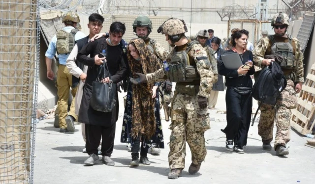 Soldiers help a women who fell due to high temperature at the Kabul International Airport