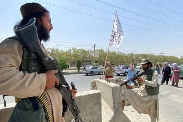 Taliban fighters stand guard at an entrance gate outside the Interior Ministry in Kabul