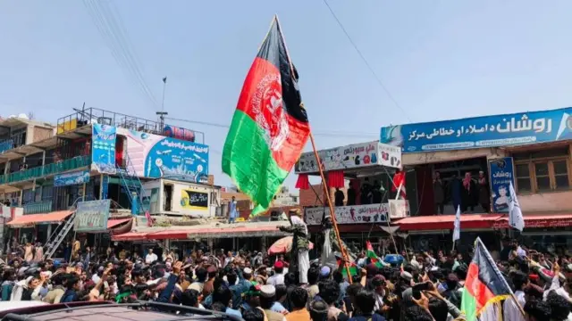 A crowd is seen with traditional Afghan flags