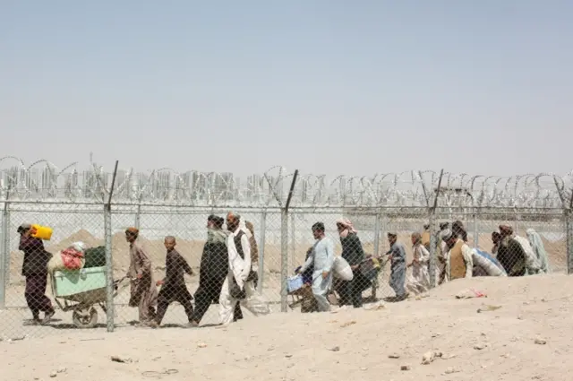 People arriving from Afghanistan cross the fence at the Friendship Gate crossing point, in the Pakistan-Afghanistan border town of Chaman,