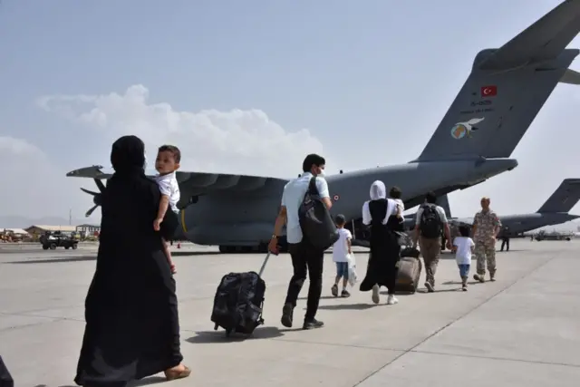 Line of Turkish citizens make their way to a Turkish military evacuation flight in Kabul on 18 August