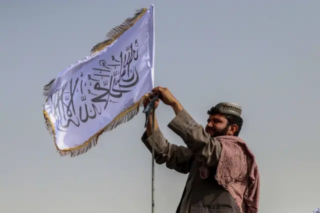 Taliban fighter raises Taliban flag on his vehicle in Kandahar on 17 August 2021