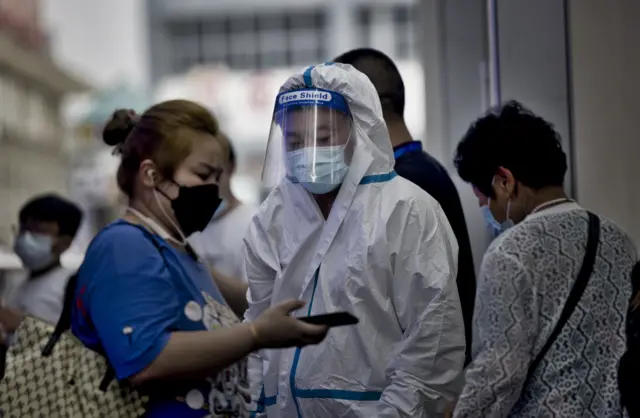 A passenger shows a health code to an official in PPE