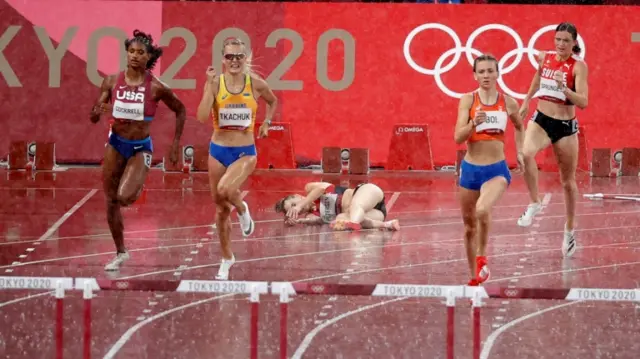 Femle Bol leads her 400m hurdles semi-final while Sara Slott Petersen lies on the track after a fall