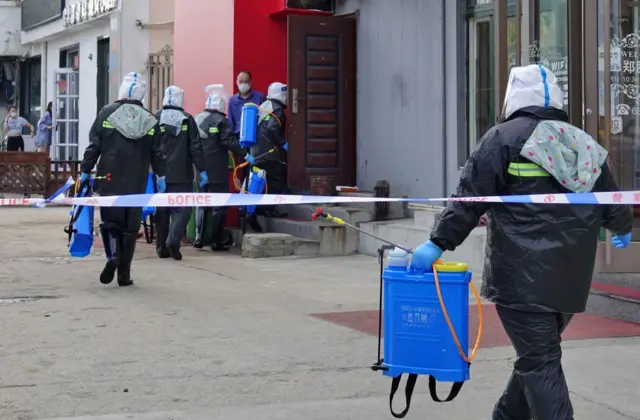 Government workers disinfect a residential block after a Covid-19 case was found in Yantai city in east China's Shandong province on 1 August 2021